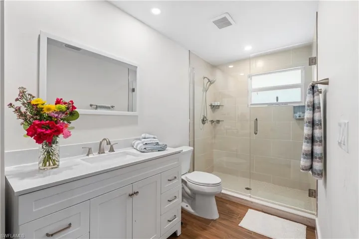 Bathroom with vanity, hardwood / wood-style floors, a shower with shower door, and toilet