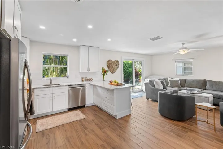 Kitchen featuring white cabinetry, light stone counters, stainless steel appliances, and kitchen peninsula