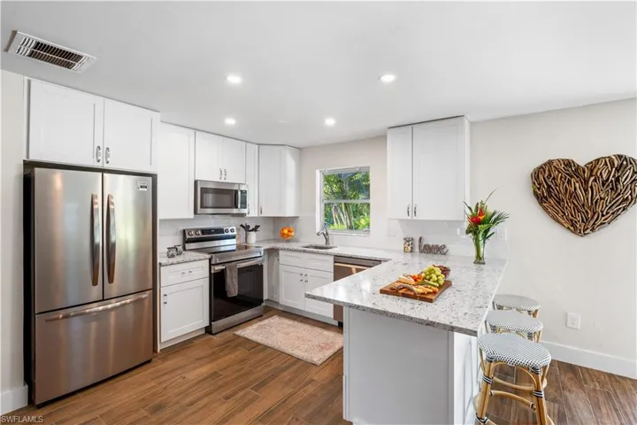 Kitchen with stainless steel appliances, white cabinetry, a kitchen breakfast bar, and kitchen peninsula