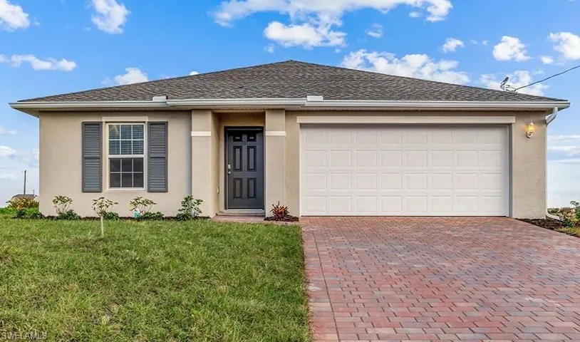 View of front of property with decorative driveway, stucco siding, a front yard, and an attached garage