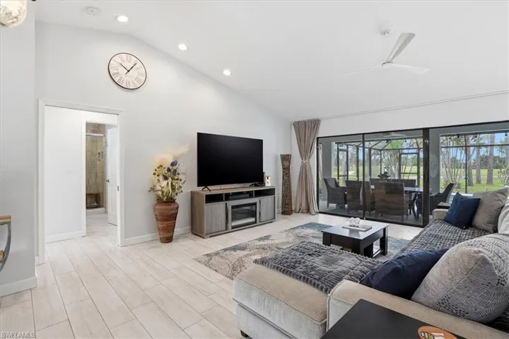 Living area featuring vaulted ceiling, wood finish floors, recessed lighting, and a ceiling fan