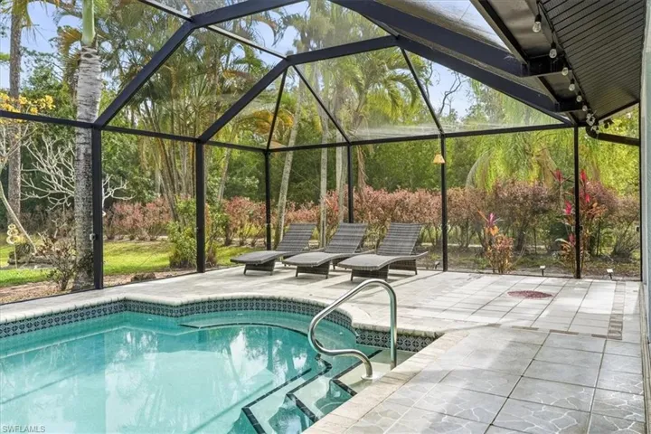 Swimming pool with glass enclosure, a sunroom, and a patio area