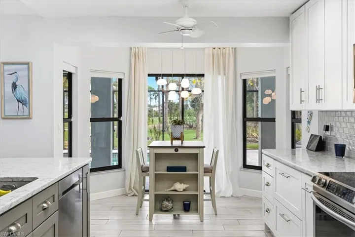 Kitchen featuring stainless steel electric stove, light stone counters, ceiling fan, wood tiled floors, and backsplash