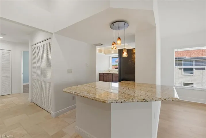 Kitchen featuring light stone countertops, pendant lighting, and stone tile floors