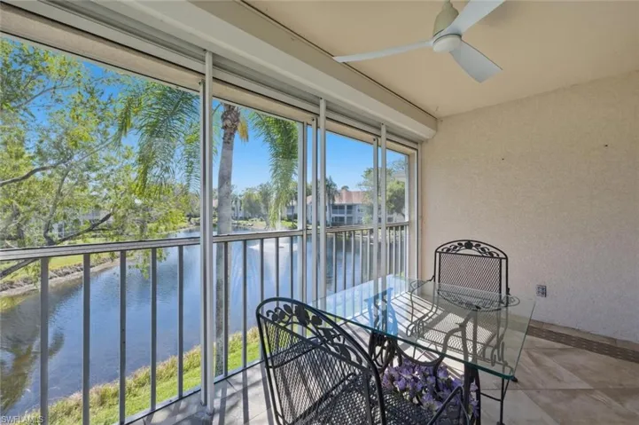 Sunroom featuring a balcony, outdoor dining space, a water view, and a ceiling fan