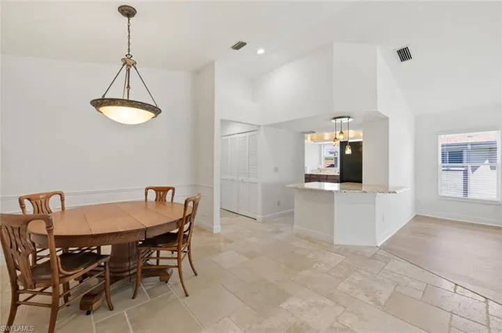 Dining space with stone tile flooring, lofted ceiling, and recessed lighting