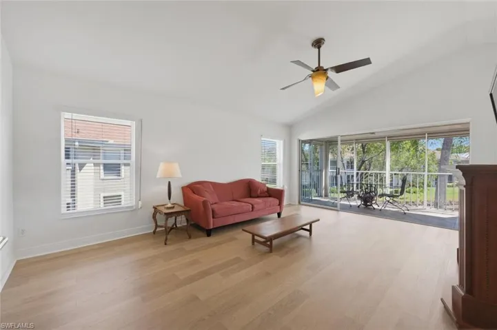 Living room featuring light wood-style floors, lofted ceiling, and ceiling fan