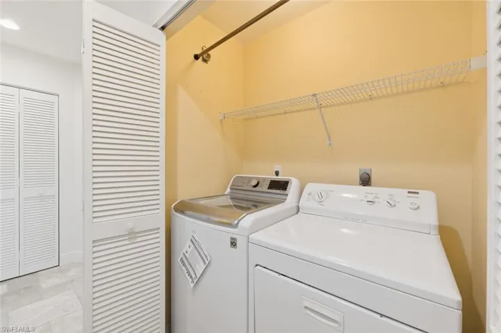 Laundry area featuring separate washer and dryer, recessed lighting, and light stone finish floors