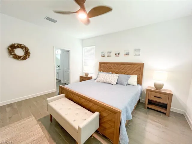 Bedroom featuring tile finished floors, ensuite bathroom, and a ceiling fan