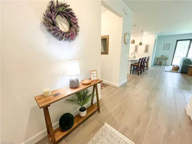 Hallway featuring light tile-style flooring and baseboards