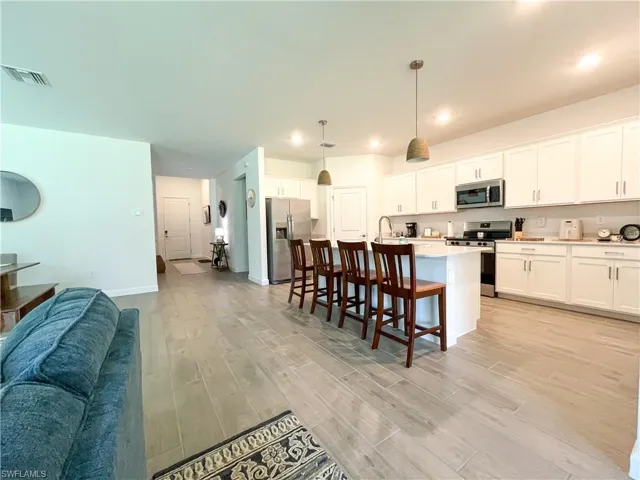 Kitchen with stainless steel appliances, light tile floors, light countertops, open floor plan, and a breakfast bar
