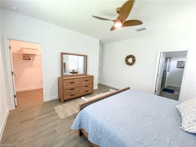 Bedroom with tiled floors, a spacious closet, and a ceiling fan