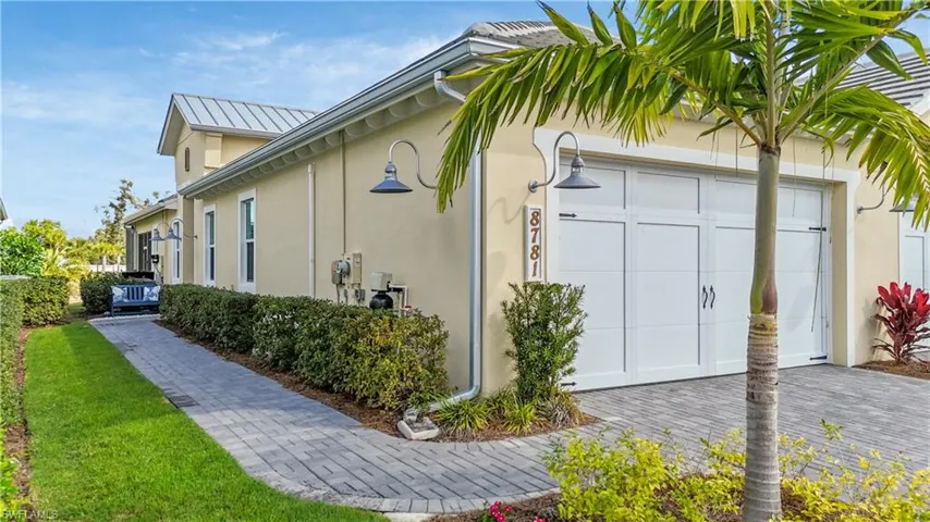 View of property exterior featuring stucco siding, a garage, decorative driveway, and a metal roof