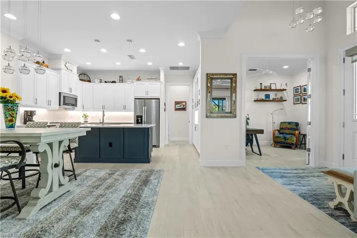Kitchen featuring decorative light fixtures, two tone color scheme, stainless steel appliances, light wood-style flooring, and light countertops