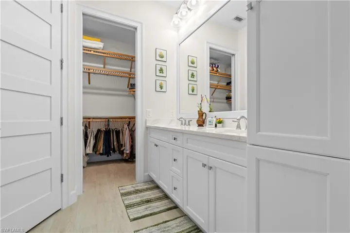 Bathroom with double vanity, a spacious closet, and light wood-type flooring