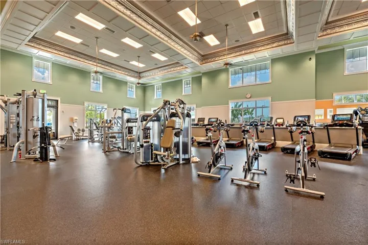 Gym with a high drop ceiling, ceiling fan, and crown molding
