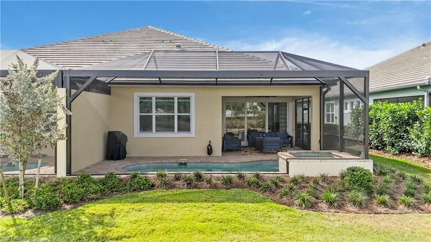 Back of house featuring stucco siding, glass enclosure, an outdoor pool, a sunroom, and a patio area