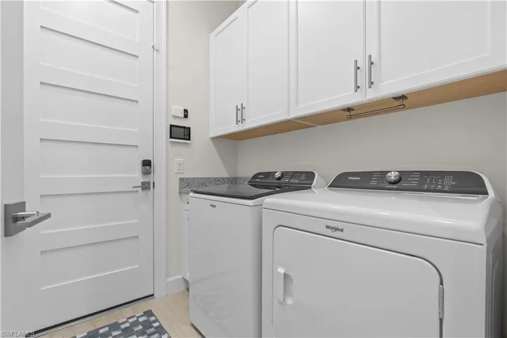 Laundry area with cabinet space, washer and dryer, and light wood-type flooring