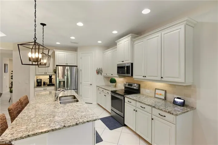 Kitchen with stainless steel appliances, light stone countertops, light tile diagonal flooring, and recessed lighting