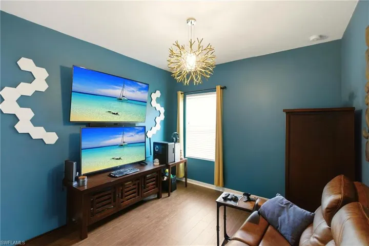 Game room with wood finished floors and a chandelier/bedroom