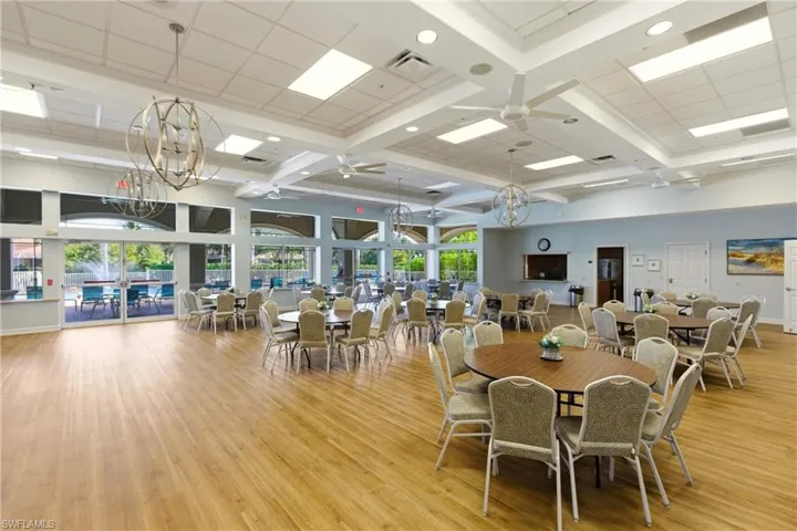 Clubhouse Dining area with a chandelier, light wood finished floors, a ceiling fan, coffered ceiling, and beam ceiling