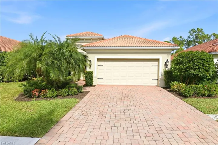 View of front of house with stucco siding, decorative driveway, a tiled roof, and a front yard