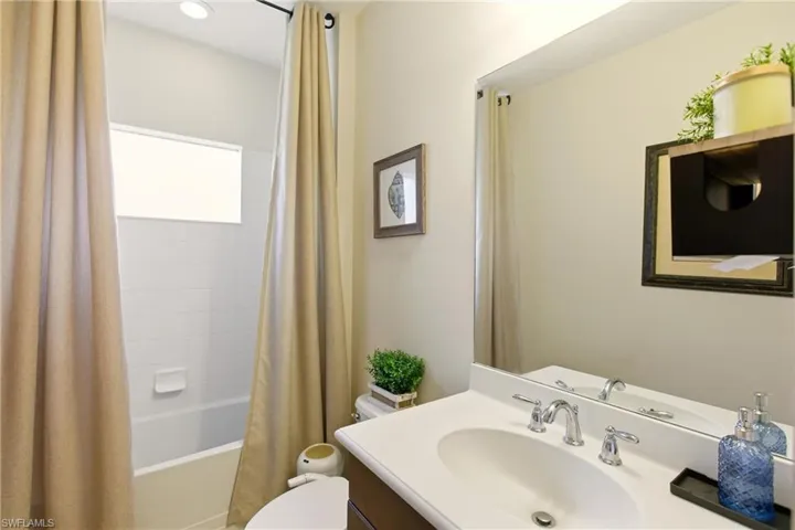 Bathroom featuring vanity, shower / bathtub combination with curtain, and recessed lighting