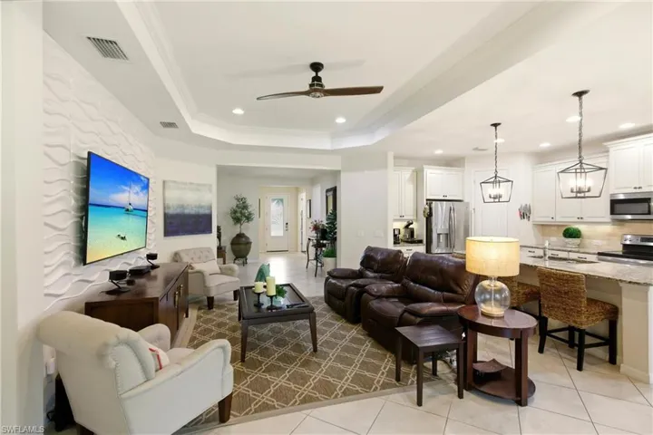 Living room with light diagonal tile floors, a tray ceiling, recessed lighting, a ceiling fan, and ornamental molding
