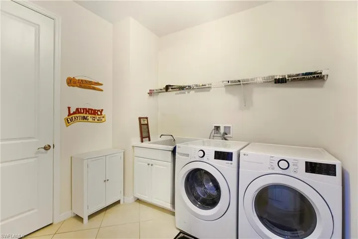 Laundry room with light tile diagonal flooring, cabinet space, laundry sink and independent washer and dryer