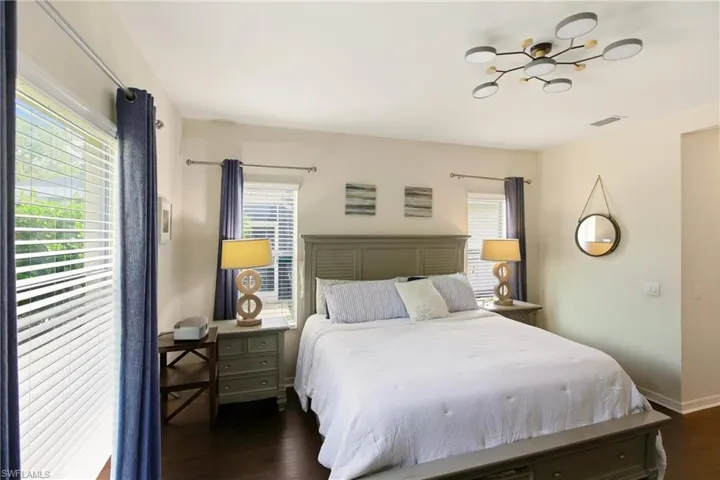 Bedroom featuring multiple windows and dark wood-style floors