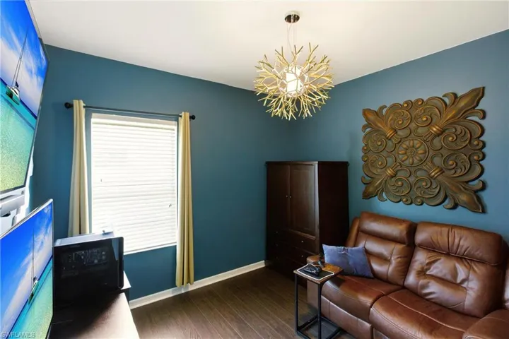 Game room with dark wood-type flooring and a chandelier/bedroom