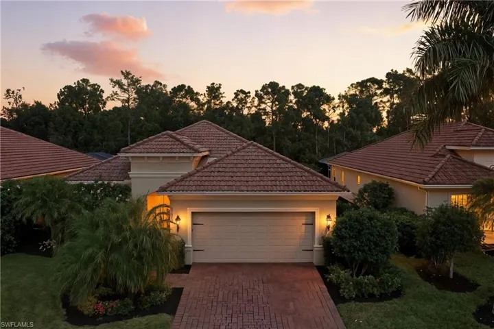 Sunset View of front of property featuring decorative driveway, a tile roof, a garage, and stucco siding