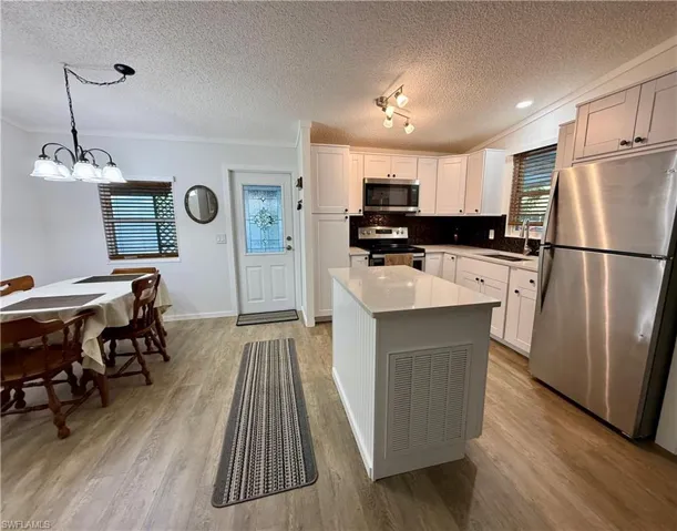 Kitchen with decorative light fixtures, white cabinetry, sink, and appliances with stainless steel finishes