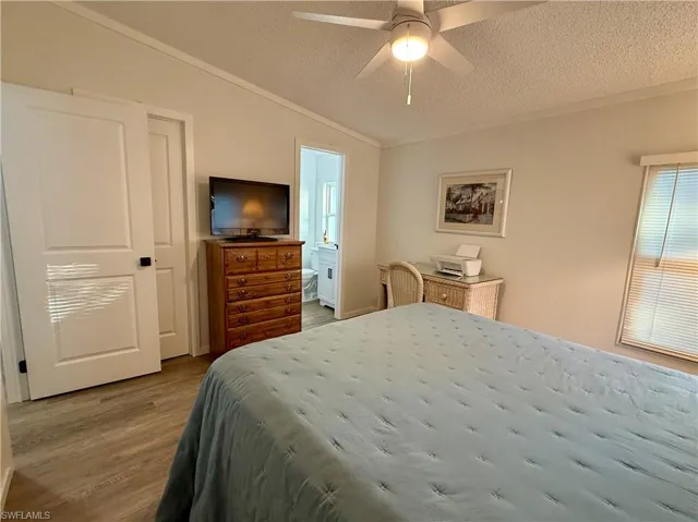 Bedroom with connected bathroom, ceiling fan, lofted ceiling, and light wood-type flooring