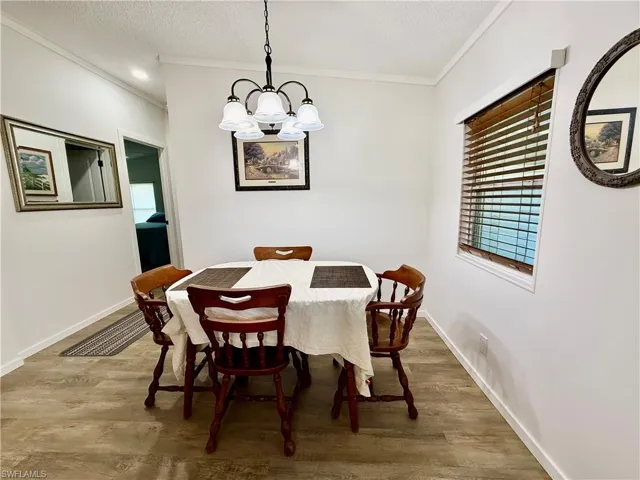 Dining area featuring hardwood / wood-style floors, a textured ceiling, ornamental molding, and a notable chandelier