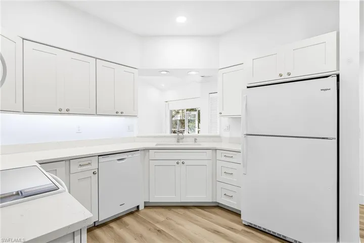 Kitchen with white appliances, white cabinets, light wood-style floors, recessed lighting, and light stone countertops