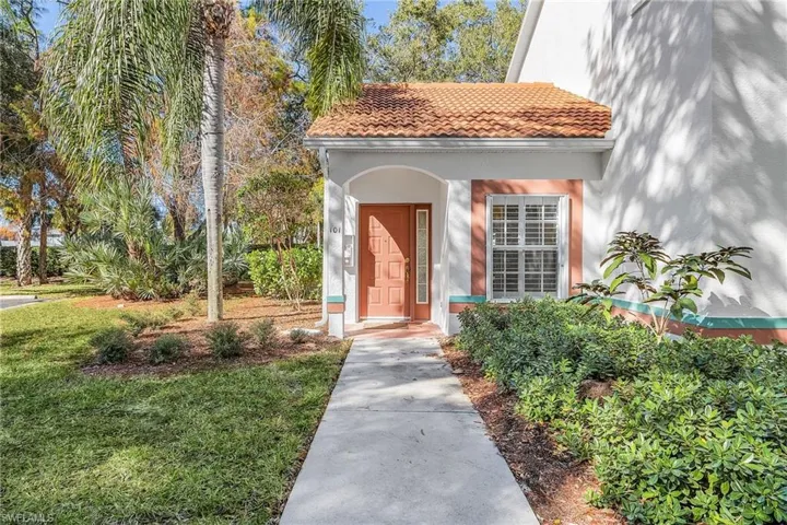 View of exterior entry with a tiled roof, stucco siding, and a lawn