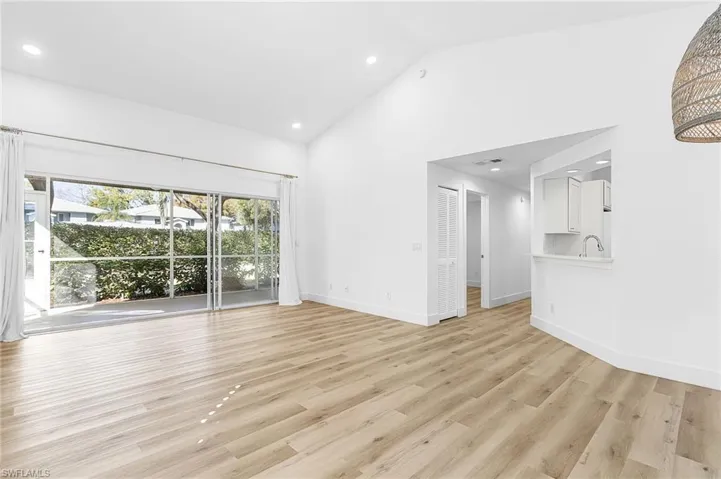 Unfurnished living room with light wood-type flooring, high vaulted ceiling, and recessed lighting
