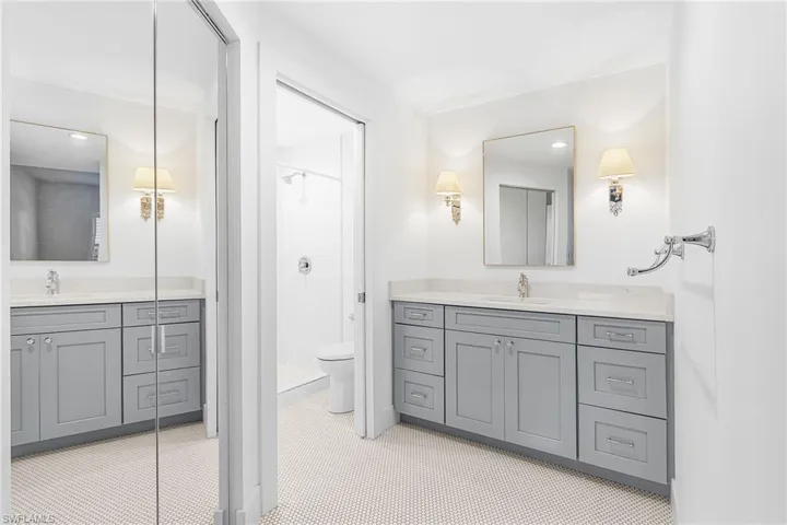 Full bath with two vanities, a shower stall, and recessed lighting