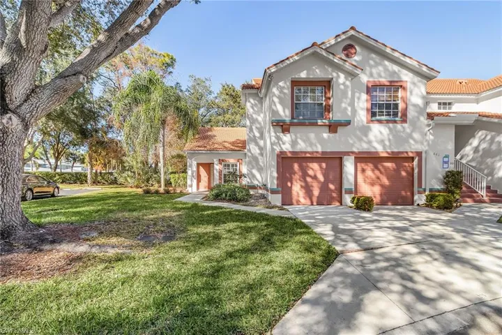 Mediterranean / spanish-style house with stucco siding, a front yard, a tile roof, driveway, and a garage