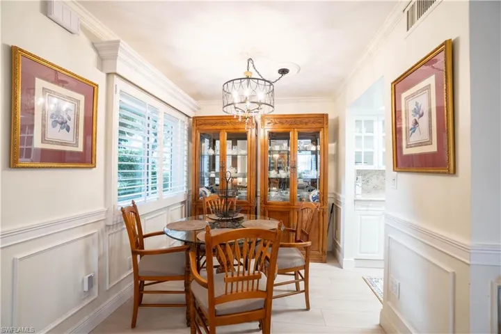 Dining room with a decorative wall, wainscoting, ornamental molding, and a chandelier