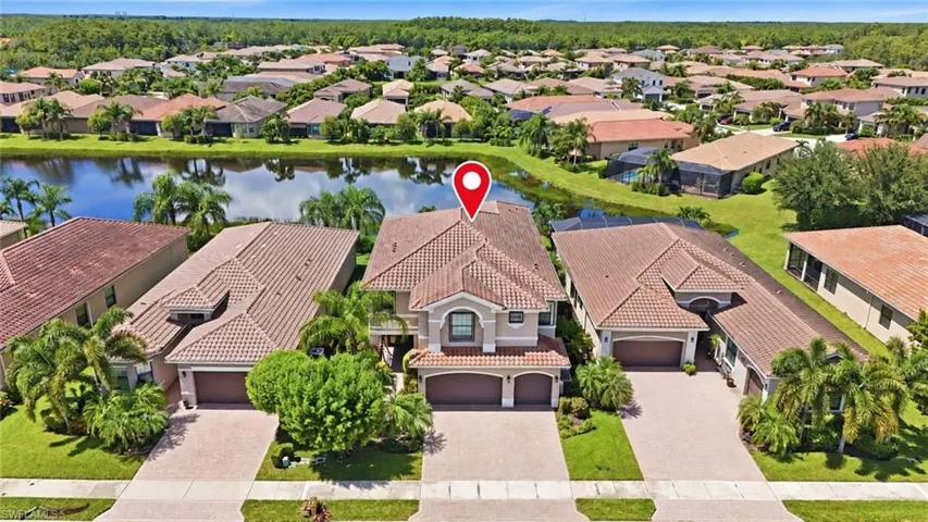 Two-story stucco exterior with a tile roof, dual garage bays, and a paver driveway