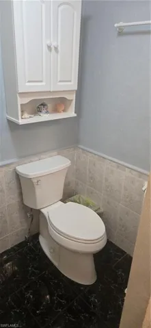Bathroom featuring wainscoting, tile walls, and a textured wall
