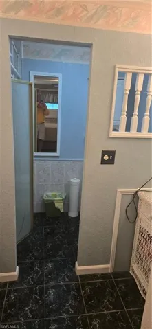 Full bath featuring a textured wall, a shower stall, and dark tile patterned flooring