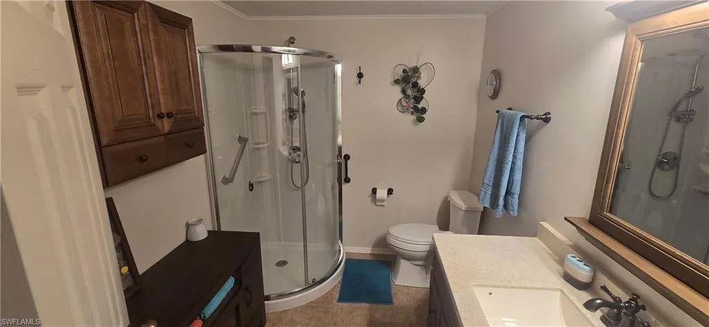 Full bathroom featuring vanity, a stall shower, dark tile patterned flooring, and ornamental molding