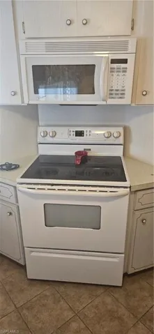 Kitchen featuring light countertops, electric stove, and dark tile patterned floors