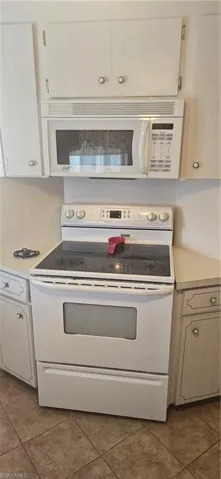 Kitchen featuring white range with electric cooktop, light countertops, and light tile patterned flooring