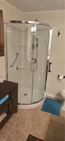 Full bathroom featuring ornamental molding, a shower stall, light tile patterned floors, and a textured ceiling