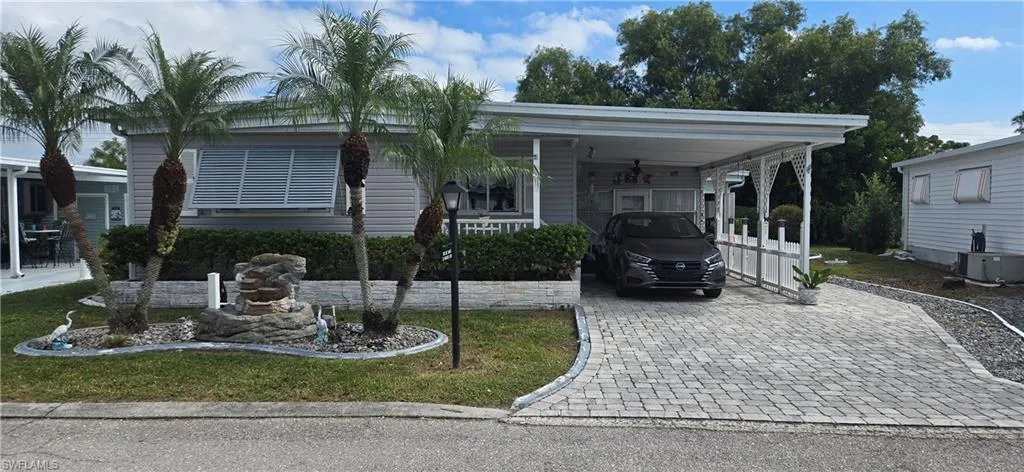Manufactured / mobile home featuring decorative driveway, an attached carport, a porch, and a front yard