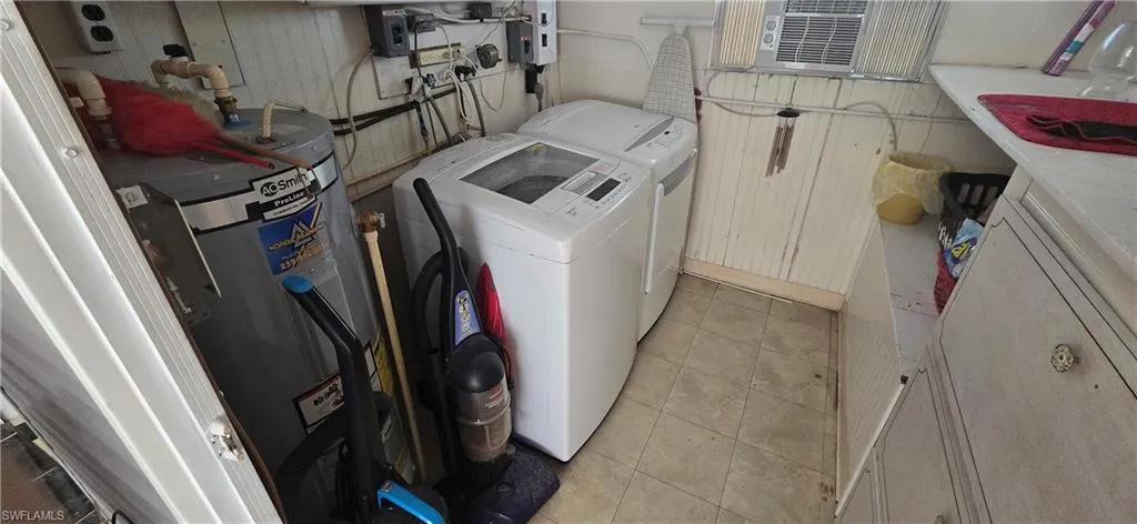 Laundry area with washing machine and clothes dryer, water heater, and light tile patterned floors